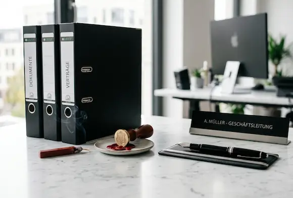 Office desk with binders, wax seal, stamp and management nameplate.