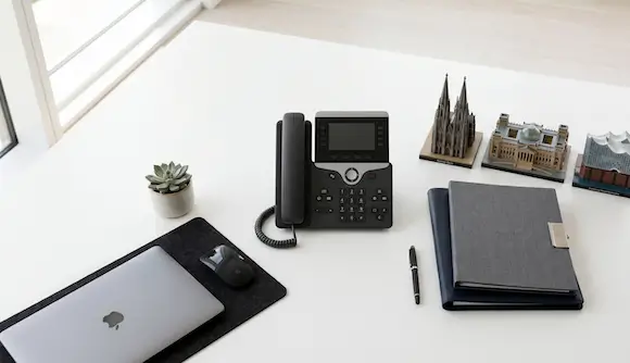 Desk with landline telephone, notebook, MacBook, and a miniature Cologne Cathedral – virtual office.